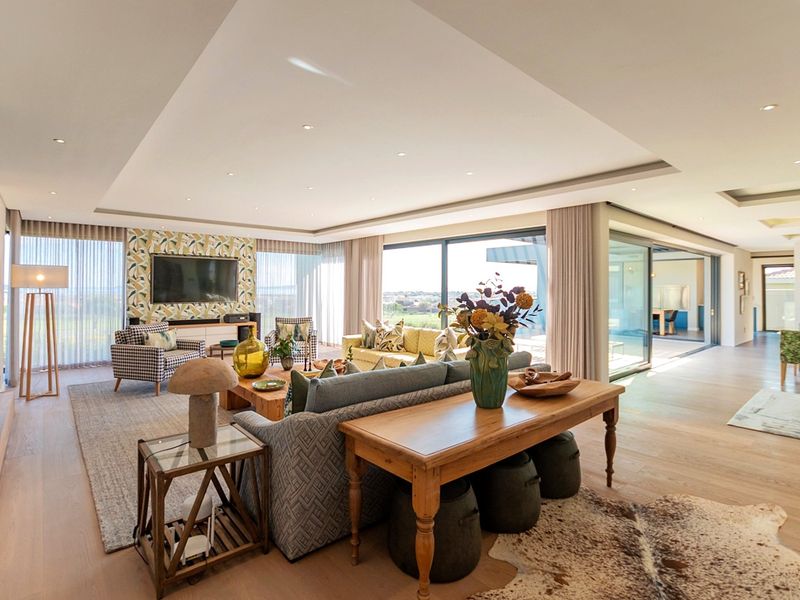 Spacious open-plan living area featuring high ceilings with recessed lighting, large sliding glass doors, and modern timber flooring with a built-in fireplace.
