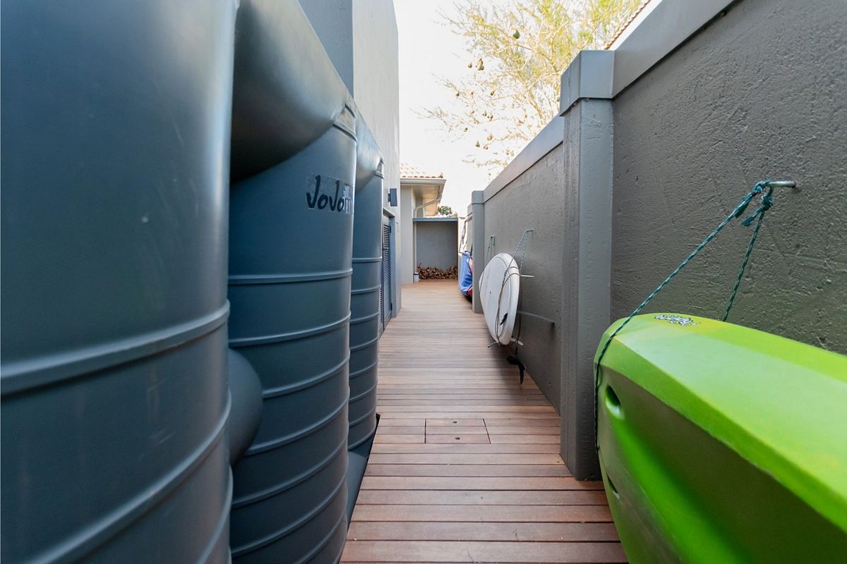 Side passage featuring timber decking and large water storage tanks installed along the boundary wall.