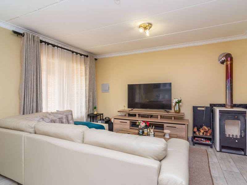A comfortable living room featuring tiled flooring, a built-in fireplace with a flue, and large windows with curtain rails.