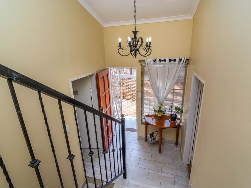 Entrance foyer featuring tiled flooring, a wrought iron staircase railing, and a classic chandelier, providing a welcoming transition into the home.