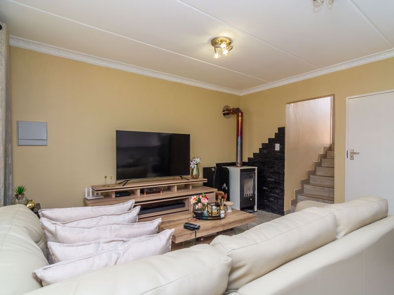A comfortable living room featuring a built-in wood-burning stove with a decorative stone feature wall and direct access to the staircase.