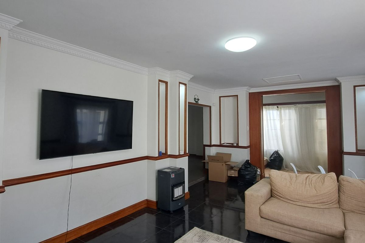 Spacious living room featuring built-in wall niches, crown molding, chair rail detailing, and dark tiled flooring.