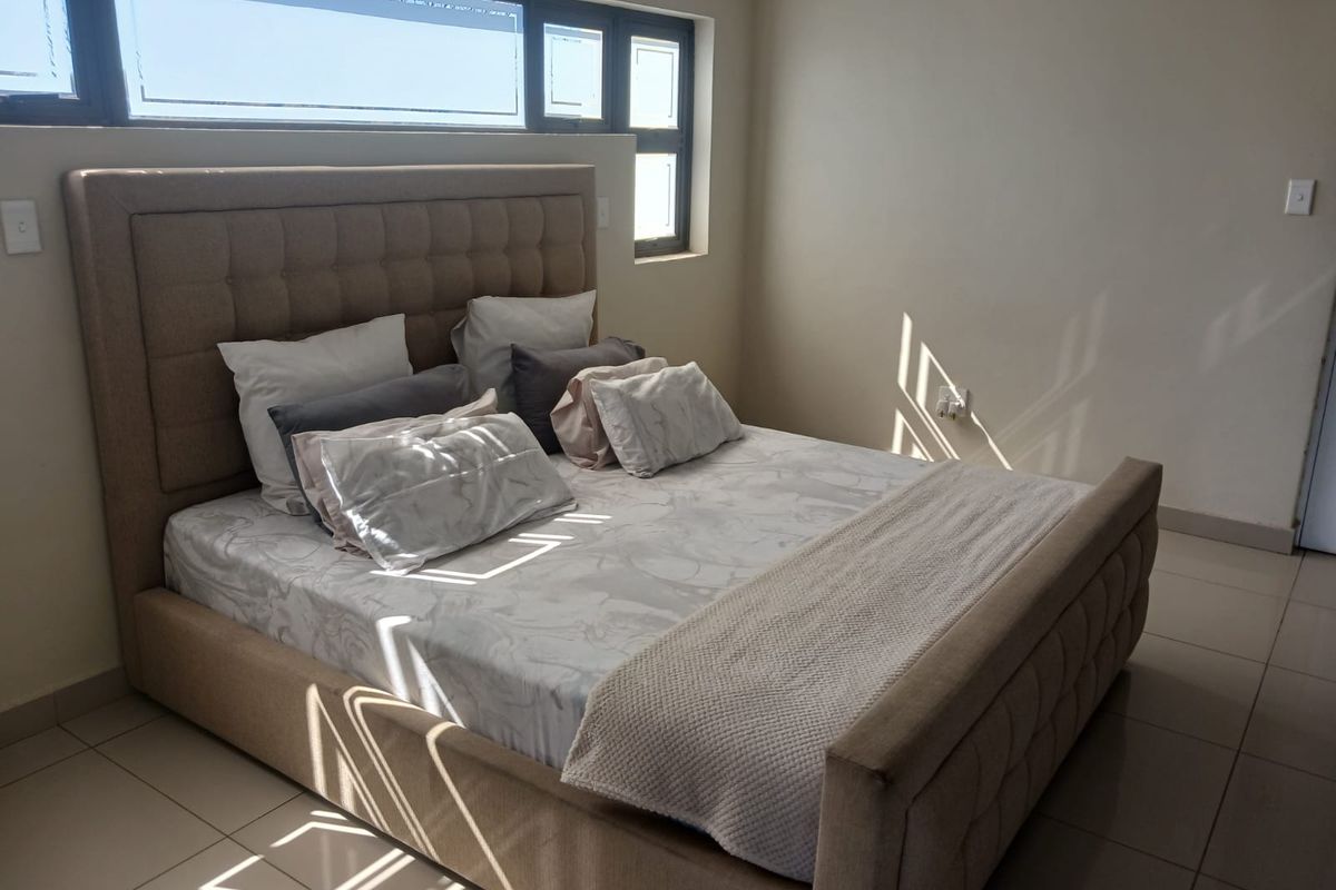 A bright bedroom featuring neutral tiled flooring and horizontal clerestory windows that allow for natural light.