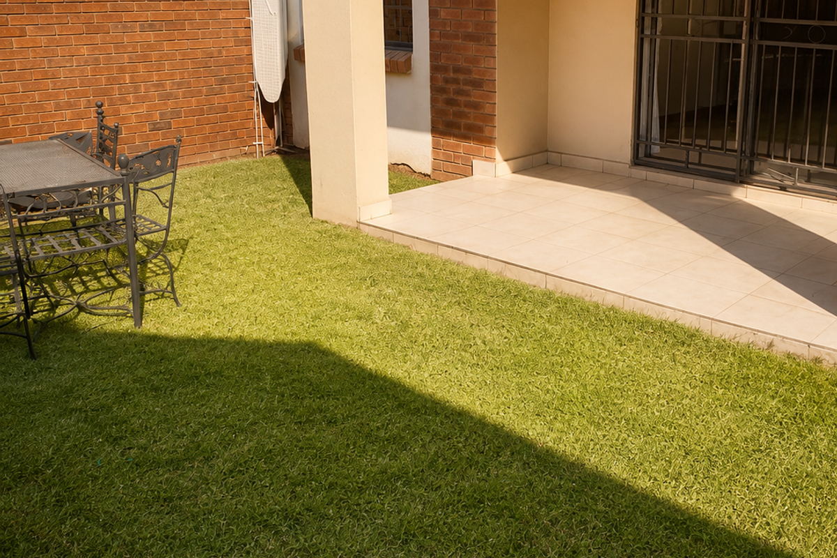 A private rear garden featuring a tiled patio area, brick boundary wall, and secure sliding door access to the apartment interior.
