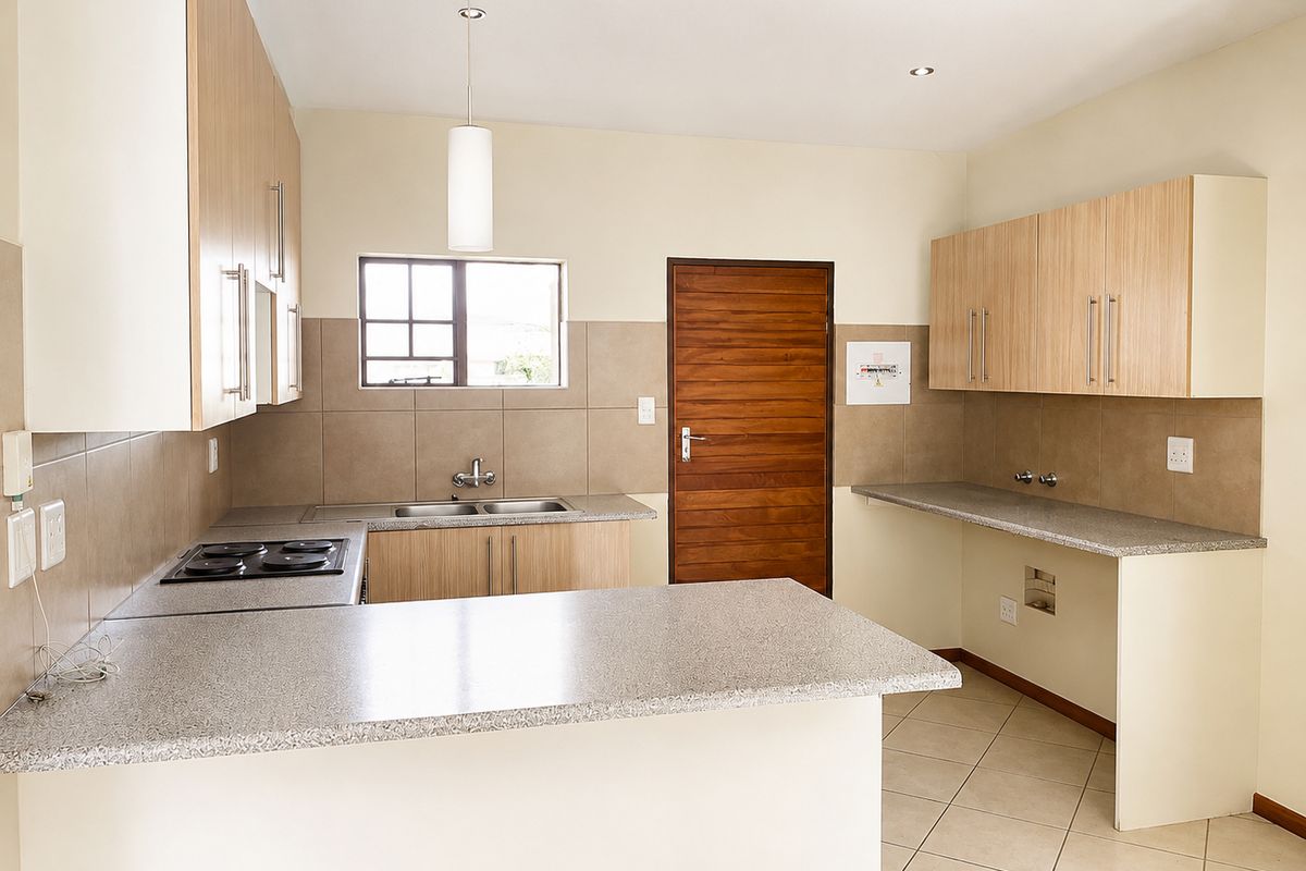 A clean, functional kitchen featuring light wood cabinetry, granite countertops, a built-in electric hob, and tiled flooring with dedicated plumbing for appliances.