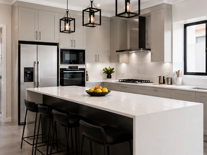 Modern kitchen featuring a large central island with quartz countertops, shaker cabinetry, integrated appliances, and stylish pendant lighting, with an adjacent laundry area.