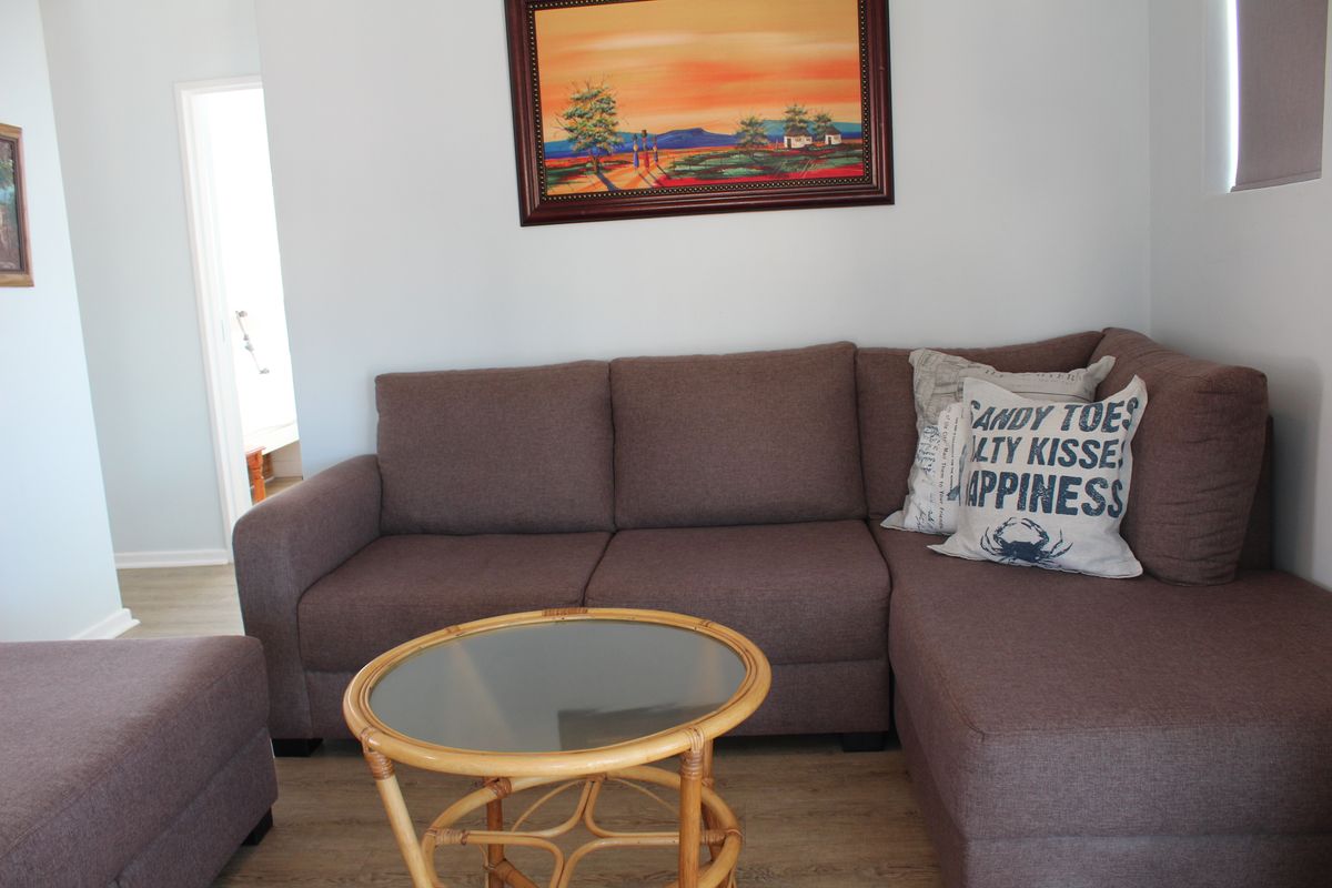 A comfortable living room area featuring light-toned laminate flooring and neutral wall finishes, providing a clean and functional space.