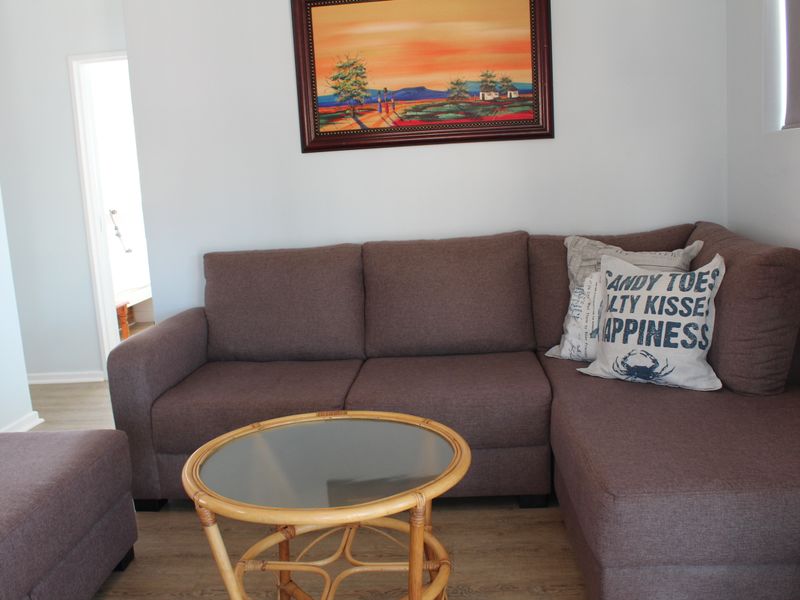 A comfortable living room area featuring light-toned laminate flooring and neutral wall finishes, providing a clean and functional space.