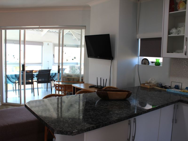 Open plan kitchen area featuring granite countertops and white cabinetry, with direct access through sliding glass doors to an outdoor patio space.