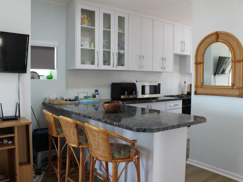 A functional kitchen featuring white cabinetry, granite countertops, and a breakfast bar, providing a practical layout for daily meal preparation.
