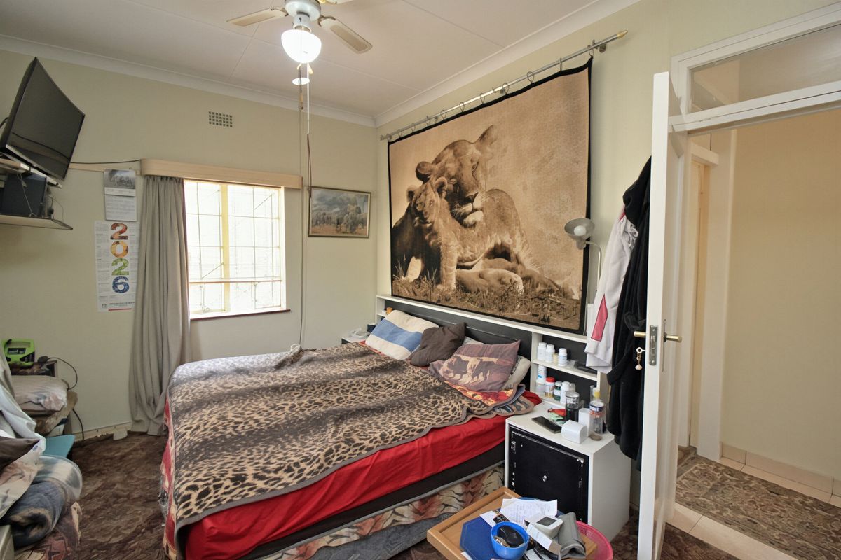A functional bedroom featuring a ceiling fan and security bars on the window, providing a standard living space.