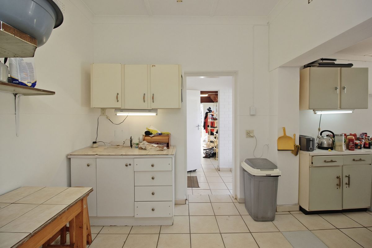 A functional kitchen space featuring tiled flooring, built-in cabinetry, and tiled countertops, offering potential for modernization and aesthetic updates.