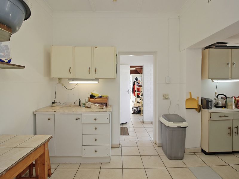 A functional kitchen space featuring tiled flooring, built-in cabinetry, and tiled countertops, offering potential for modernization and aesthetic updates.