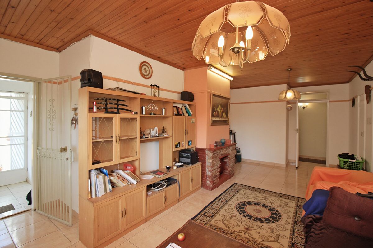 Living room featuring a timber ceiling, tiled flooring, and a brick fireplace, offering a dated aesthetic with potential for modernization.