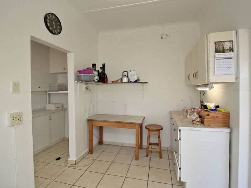 A functional scullery area featuring built-in cabinetry, tiled flooring, and laminate countertops, offering additional prep and storage space adjacent to the main kitchen.