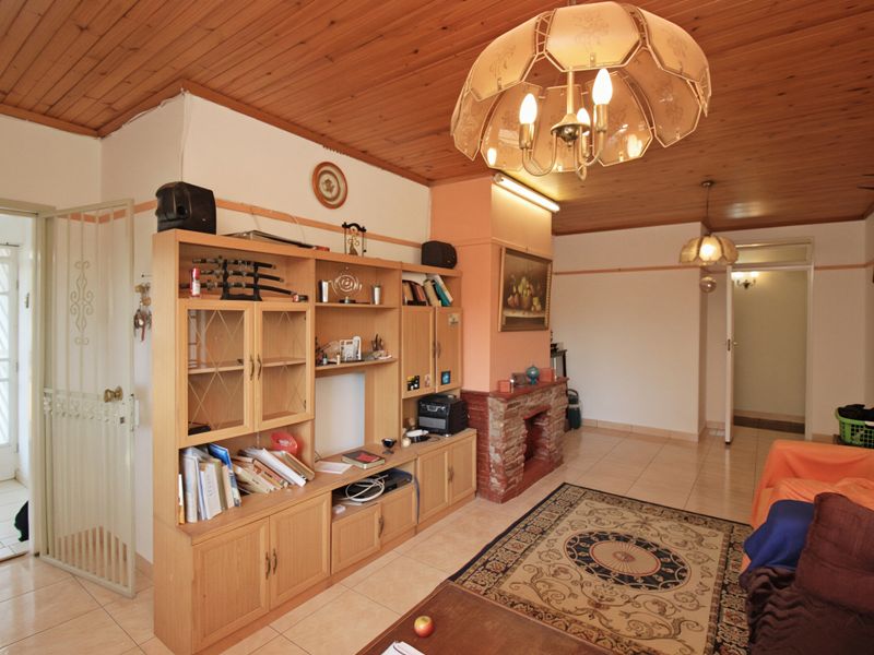 Living room featuring a timber-clad ceiling, tiled flooring, and a traditional brick fireplace, offering a dated but functional space.