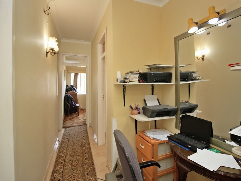 A functional hallway featuring tiled flooring, wall-mounted lighting, and built-in shelving, providing access to adjacent rooms.