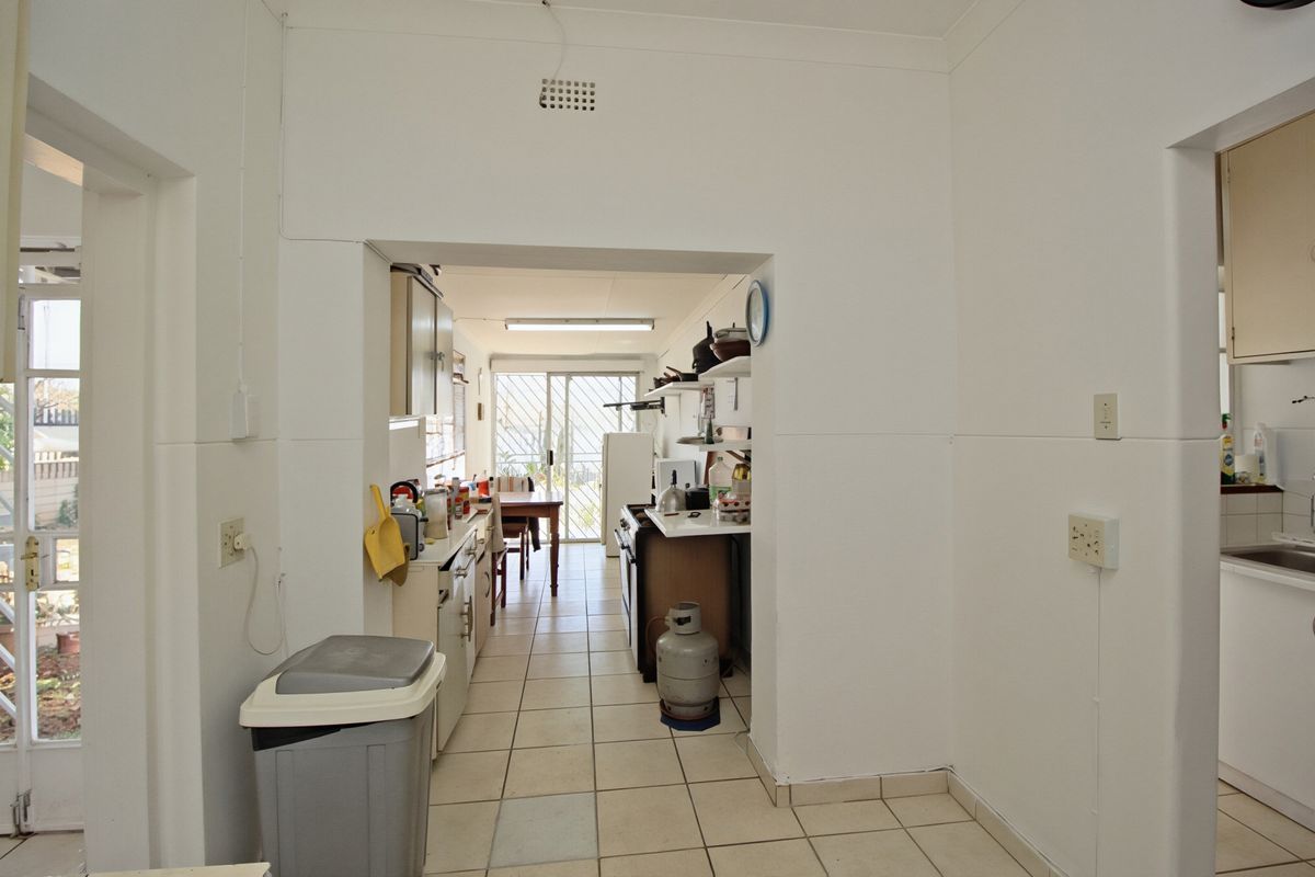A functional kitchen area featuring tiled flooring, built-in cabinetry, and direct access to an outdoor space through a sliding glass door.