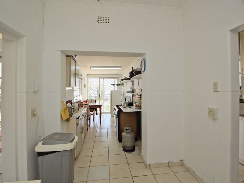 A functional kitchen area featuring tiled flooring, built-in cabinetry, and direct access to an outdoor space through a sliding glass door.