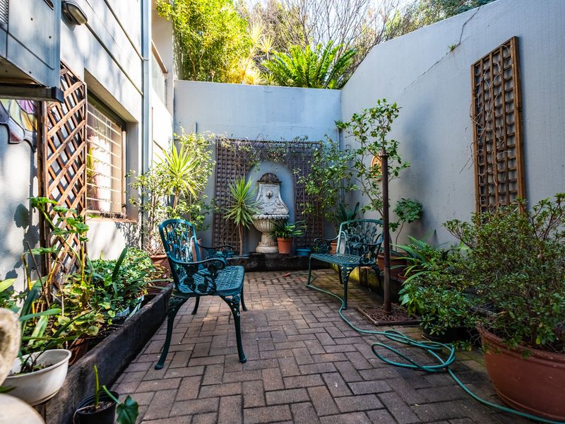A private courtyard patio featuring brick paving, a decorative wall fountain, and trellis panels, offering a quiet outdoor space for relaxation.