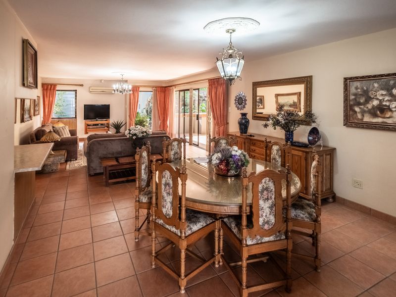 Spacious open-plan living and dining area featuring ceramic tile flooring, a ceiling rose, and sliding glass doors leading to an outdoor space.