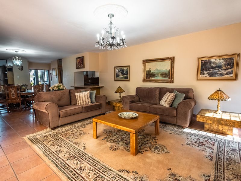 Spacious open-plan living and dining area featuring ceramic tile flooring, decorative ceiling roses, and elegant crystal chandeliers.