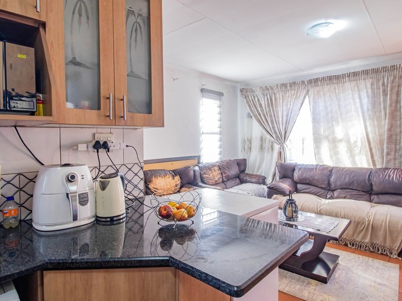 Open-plan kitchen and living area featuring granite countertops, built-in cabinetry, and tiled flooring, creating a functional and connected living space.
