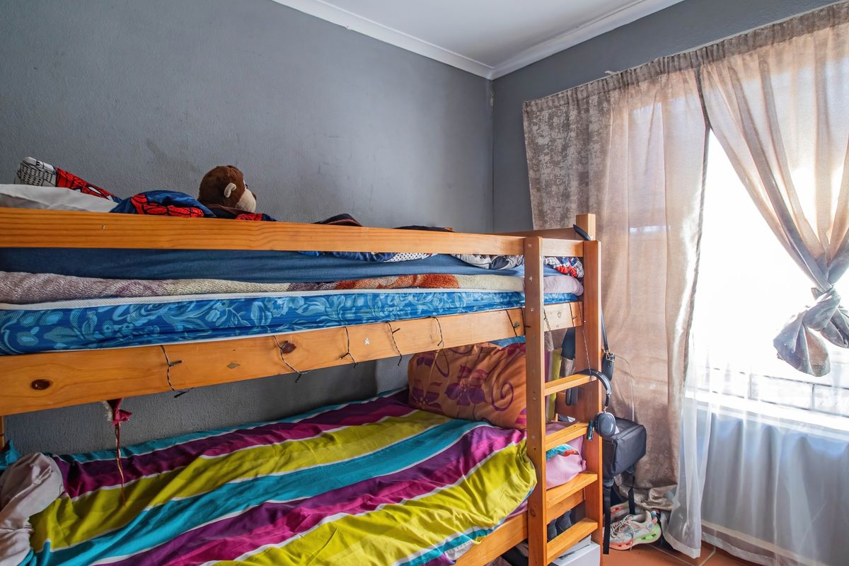 A bedroom featuring grey walls and a window with installed curtain rails, providing natural light to the space.