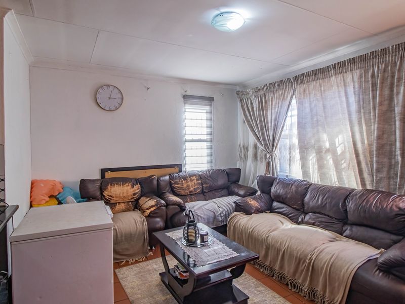 Open plan living area featuring tiled flooring, window blinds, and curtain tracks, offering a functional space with potential for cosmetic updates.