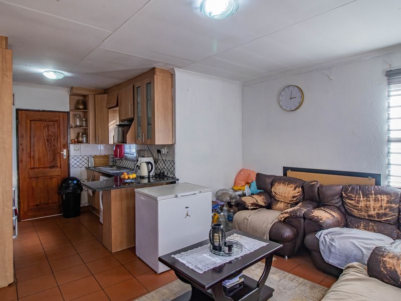 Open plan living area featuring a compact kitchen with laminate cabinetry, granite countertops, and tiled flooring throughout.