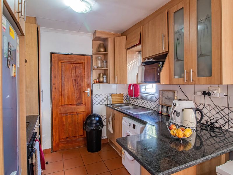 Functional kitchen featuring laminate cabinetry, granite countertops, tiled backsplash, and integrated laundry plumbing, offering a practical layout for daily use.