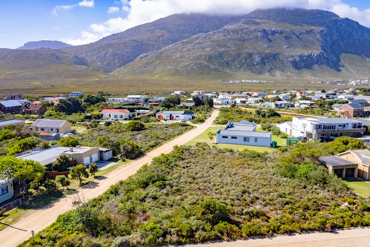 Aerial view of a vacant residential plot situated in a coastal neighborhood with mountain views.
