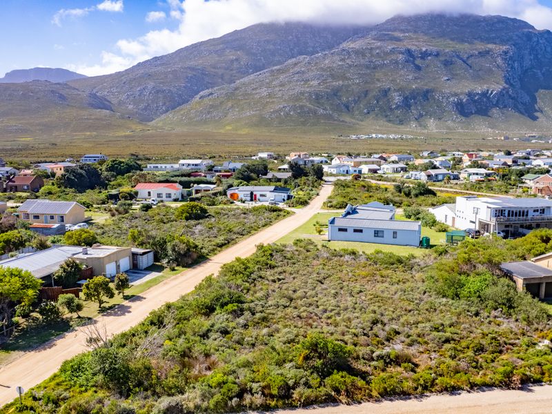 Aerial view of a vacant residential plot situated in a coastal neighborhood with mountain views.