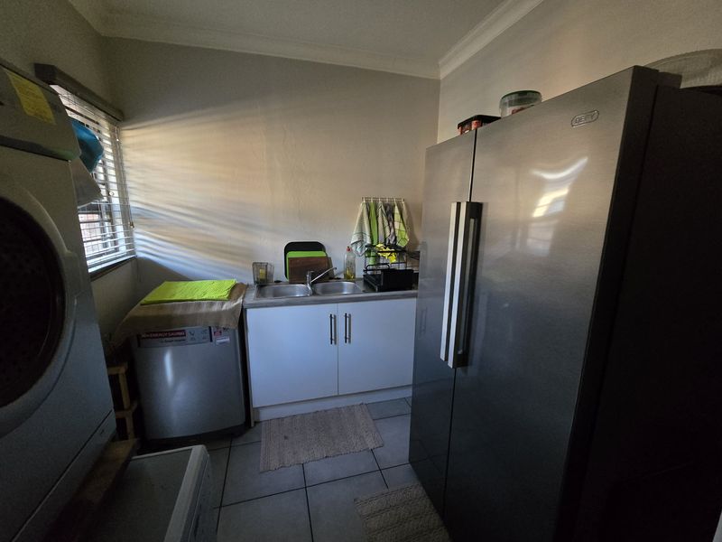 A functional laundry area featuring built-in cabinetry, a double stainless steel sink, and tiled flooring, providing practical utility space for the home.