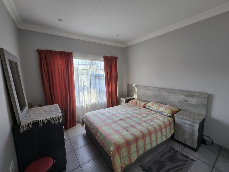 A functional bedroom featuring tiled flooring, recessed ceiling lights, and a built-in headboard with integrated bedside tables.