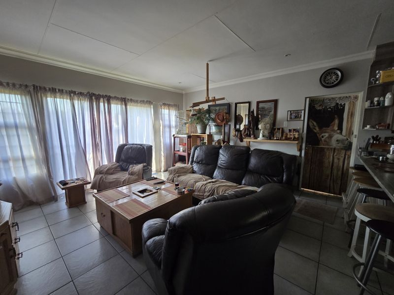Open plan living area featuring tiled flooring, recessed lighting, and large sliding glass doors providing natural light, with an integrated breakfast bar.