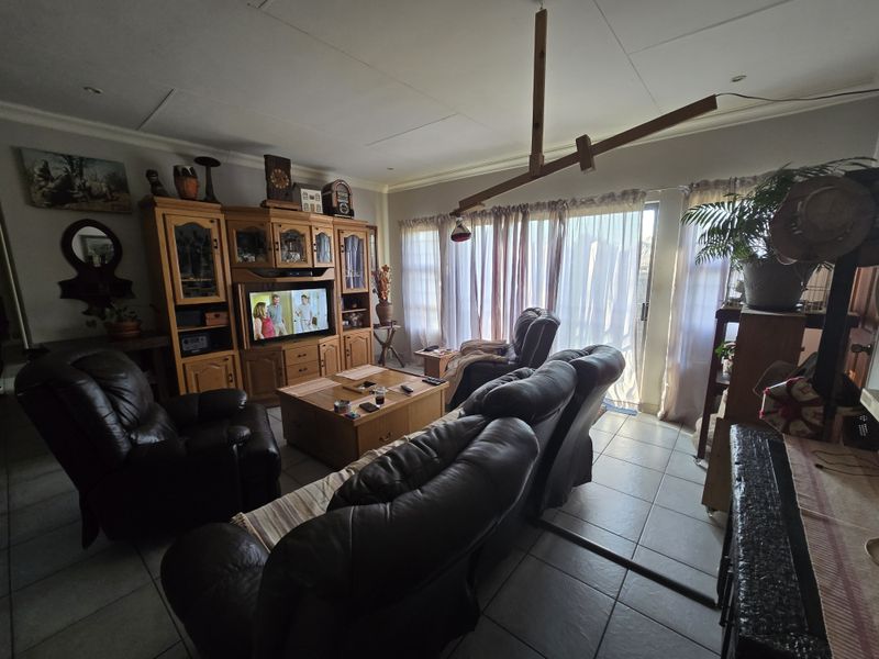 A living room featuring tiled flooring and a sliding glass door providing access to the exterior, with recessed ceiling lighting.