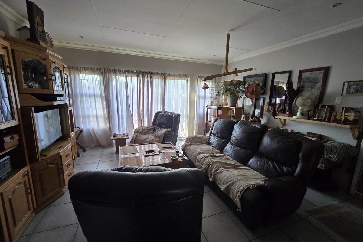 A spacious living room featuring tiled flooring, recessed lighting, and large sliding glass doors that provide ample natural light.