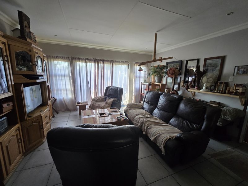 A spacious living room featuring tiled flooring, recessed lighting, and large sliding glass doors that provide ample natural light.
