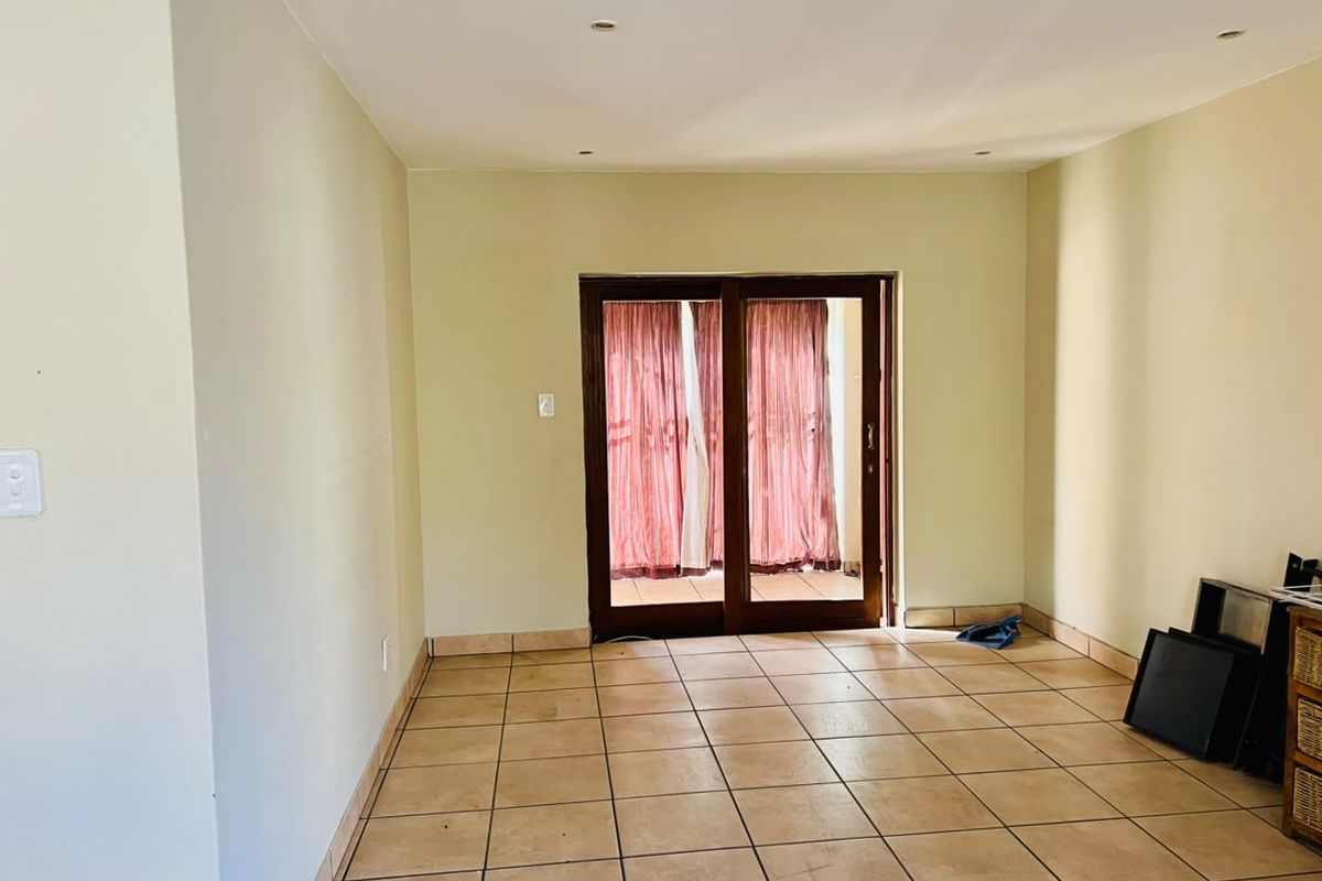 An empty living room featuring tiled flooring, recessed downlights, and a sliding glass door providing access to the exterior.