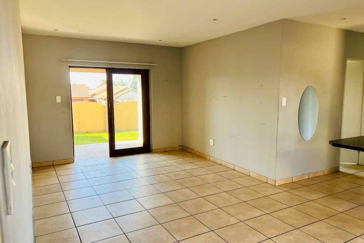 An empty living room featuring tiled flooring, recessed lighting, and a sliding glass door providing direct access to the outdoor patio area.