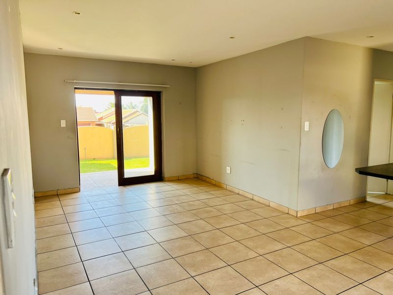 An empty living room featuring tiled flooring, recessed lighting, and a sliding glass door providing direct access to the outdoor patio area.