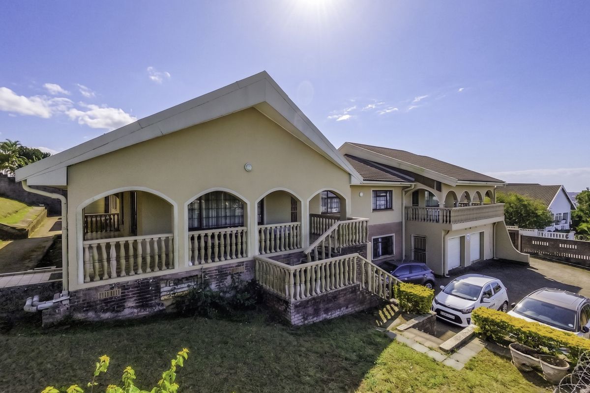 Rear elevation of a multi-level house featuring an arched veranda, external staircase, and paved driveway area.
