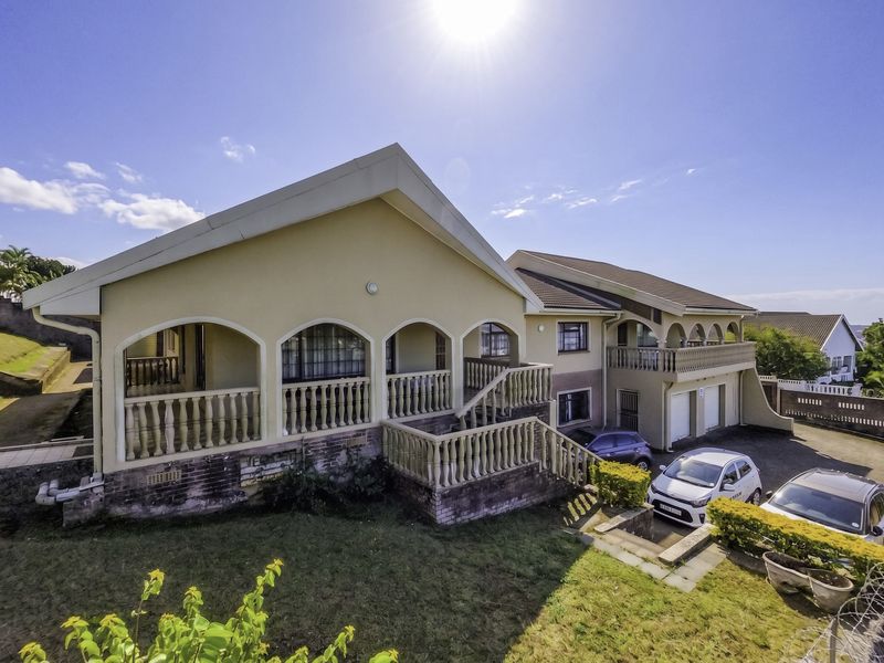 Rear elevation of a multi-level house featuring an arched veranda, external staircase, and paved driveway area.