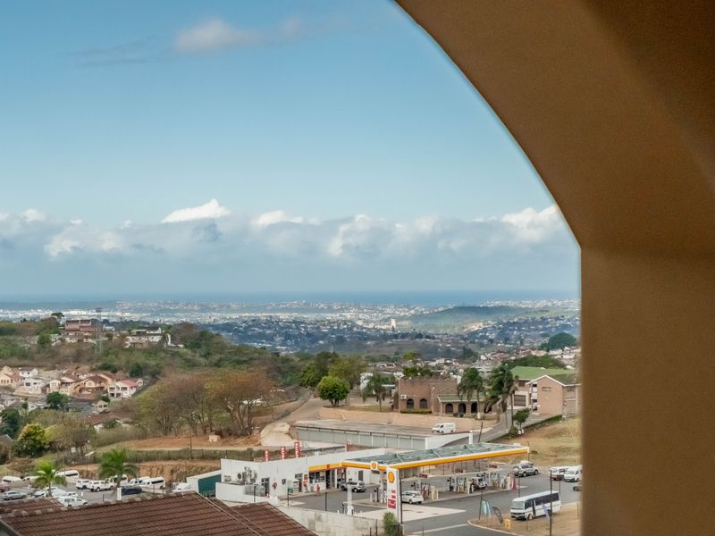 A scenic elevated view overlooking the surrounding neighborhood, coastal landscape, and local infrastructure, framed by a structural arched opening.
