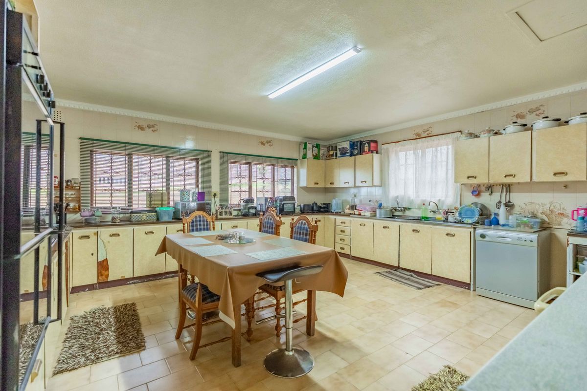 Spacious kitchen featuring extensive built-in cabinetry, double wall ovens, and tiled flooring, offering a functional layout with significant potential for modern renovation.
