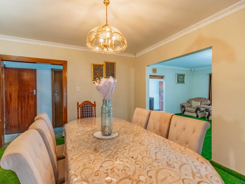A traditional dining room featuring crown molding, an ornate pendant light, and direct access to an adjacent living area.