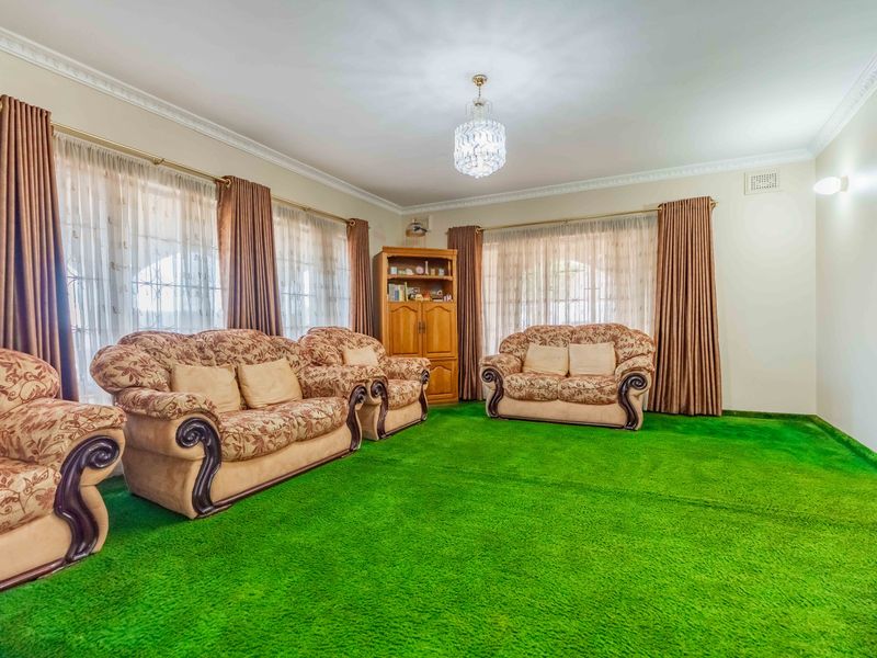 Spacious living room featuring crown molding, a crystal chandelier, and wall-to-wall carpeting, offering a classic layout with ample natural light.