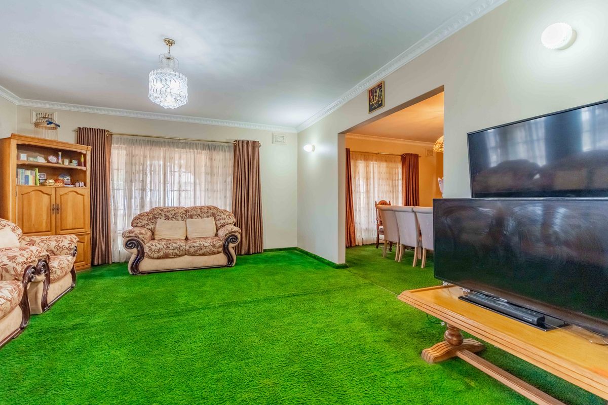 Spacious living area featuring crown molding and classic lighting fixtures, connected to an adjacent dining space.