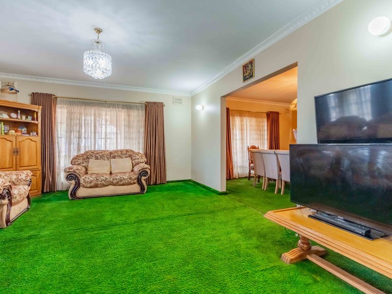 Spacious living area featuring crown molding and classic lighting fixtures, connected to an adjacent dining space.